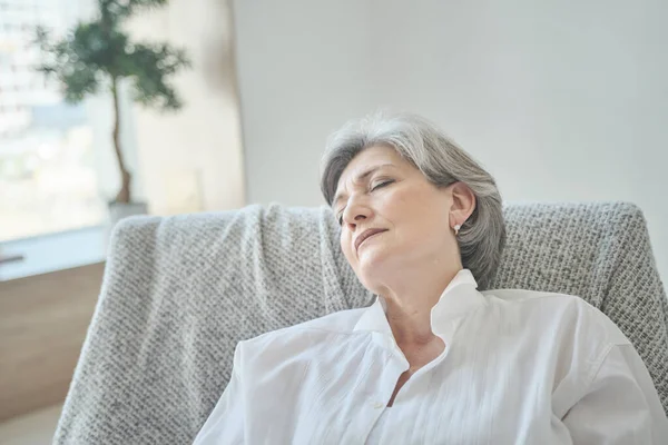 Een oudere vrouw sluimert in een comfortabele stoel, ontspant en rust haar energie — Stockfoto