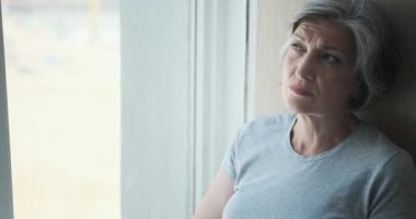 Yaşlı, düşünceli, özürlü yaşlı bir kadın hastaneden dışarı bakıyor ve gülümsüyor.