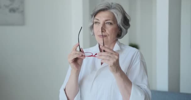 Die fröhliche, ältere Geschäftsfrau trägt eine Brille und lächelt selbstbewusst — Stockvideo