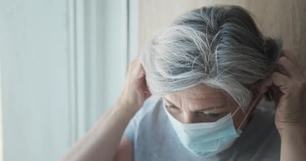 Anciana triste mujer está poniendo una máscara sentado en la ventana en el hospital — Vídeos de Stock