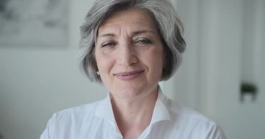 Neşeli yaşlı, olgun bir iş kadını kameraya gülümsüyor.