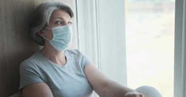 Maske takan üzgün, hasta, yaşlı bir kadın. Sağlık sorunları ve hastalıktan korkuyor.,
