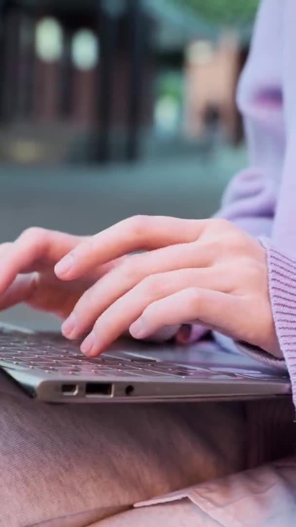 Молода жінка в фіолетовому пуловері типу рук на чорному ноутбуці — стокове відео