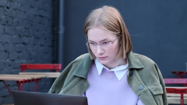Продумана молода бізнес-леді друкує на ноутбуці зовні у вуличному кафе — стокове відео