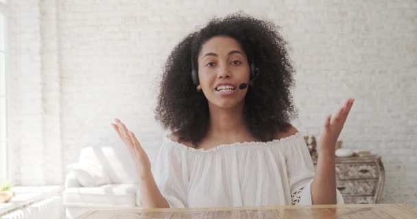 Egy vidám fekete hölgy lector nézi a webkamerát, integet a kezével és üdvözöl egy online előadást.. — Stock videók
