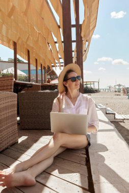 Kumsalda dizüstü bilgisayar kullanan genç bir kadın. Serbest çalışma kavramı
