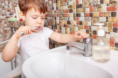 Diş fırçasıyla dişlerini fırçalayan çocuğun yakın çekimi. Mutlu çocuk banyo odasında küçük dişlerini fırçalıyor. Sağlıklı küçük çocuğun portresi mutlu bir yüzle dişlerini temizlemekten zevk alır. Diş Konsepti