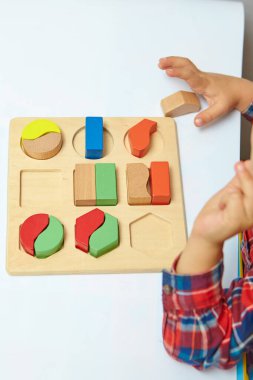 Çocuk bir tasnif makinesi topluyor. Çocuklar için eğitici mantık oyuncakları. Çocukların elleri, yakın plan. Çocuk Gelişimi için Montessori Oyunları. Beyaz arkaplanda çok renkli mantık sıralayıcı.