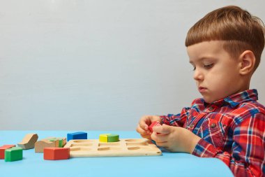 Oğlan odasında oyun oynuyor. Şekil ve renkleri öğreniyorum. Bir çocuk ayırıcıyla oynuyor. Çocuklar için eğitici mantık oyuncakları. Çocuk Gelişimi için Montessori Oyunları.