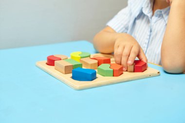 Çocuk bir tasnif makinesi topluyor. Çocuklar için eğitici mantık oyuncakları. Çocukların elleri, yakın plan. Çocuk Gelişimi için Montessori Oyunları. Beyaz arkaplanda çok renkli mantık sıralayıcı.