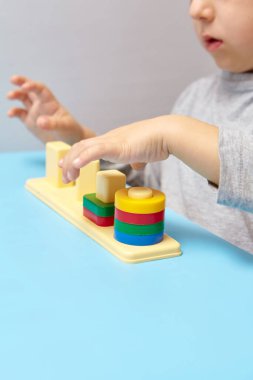 Çocuk bir tasnif makinesi topluyor. Çocuklar için eğitici mantık oyuncakları. Çocukların elleri, yakın plan. Çocuk Gelişimi için Montessori Oyunları. Beyaz arkaplanda çok renkli mantık sıralayıcı.