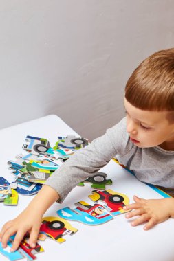 Çocuk bulmacalarla oynuyor. Oğlan odasında oyun oynuyor. Çocuklar için eğitici mantık oyuncakları