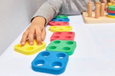 Çocuk bir tasnif makinesi topluyor. Çocuklar için eğitici mantık oyuncakları. Çocukların elleri, yakın plan. Çocuk Gelişimi için Montessori Oyunları. Beyaz arkaplanda çok renkli mantık sıralayıcı.