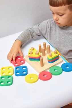Oğlan odasında oyun oynuyor. Şekil ve renkleri öğreniyorum. Bir çocuk ayırıcıyla oynuyor. Çocuklar için eğitici mantık oyuncakları. Çocuk Gelişimi için Montessori Oyunları.