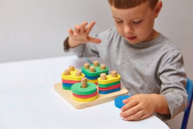 Oğlan odasında oyun oynuyor. Şekil ve renkleri öğreniyorum. Bir çocuk ayırıcıyla oynuyor. Çocuklar için eğitici mantık oyuncakları. Çocuk Gelişimi için Montessori Oyunları.