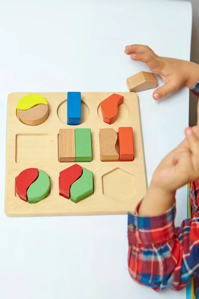 Çocuk bir tasnif makinesi topluyor. Çocuklar için eğitici mantık oyuncakları. Çocukların elleri, yakın plan. Çocuk Gelişimi için Montessori Oyunları. Beyaz arkaplanda çok renkli mantık sıralayıcı.
