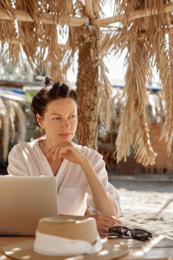 Kumsalda dizüstü bilgisayar kullanan genç bir kadın. Serbest çalışma kavramı