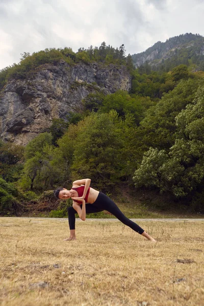 Yoga classes in nature. The concept of playing sports alone. Social exclusion. A woman does yoga in the mountains