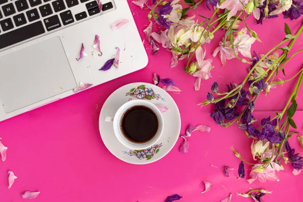 Merkez ofis masası. Dizüstü bilgisayarı, kahve fincanı, pembe arka planda çiçekleri ve taç yaprakları olan bir kadın çalışma alanı. Düz yerde, üst tarafta. Moda blogu bakışı. Metnini ekle.