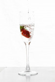 Plnění sklenice šampaňského s jahodami izolované na bílém pozadí kopírovat prostor