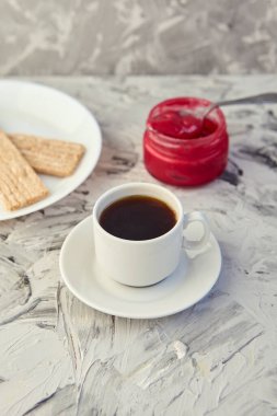 Kahvaltı için reçelli çıtır ekmek ve gri bir arka plan. Köpüklü bir kavanoz taze bal bir fincan kahvenin yanında. En az kalori. uygun beslenme