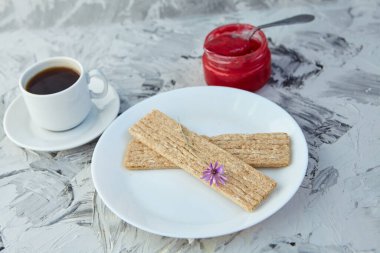 Kahvaltı için reçelli çıtır ekmek ve gri bir arka plan. Köpüklü bir kavanoz taze bal bir fincan kahvenin yanında. En az kalori. uygun beslenme