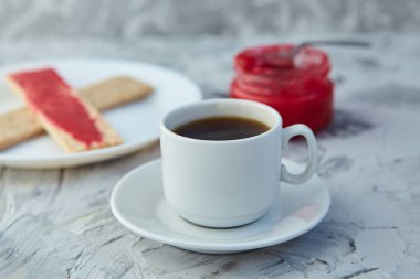 Kahvaltı için reçelli çıtır ekmek ve gri bir arka plan. Köpüklü bir kavanoz taze bal bir fincan kahvenin yanında. En az kalori. uygun beslenme