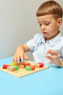 Oğlan odasında oyun oynuyor. Şekil ve renkleri öğreniyorum. Bir çocuk ayırıcıyla oynuyor. Çocuklar için eğitici mantık oyuncakları. Çocuk Gelişimi için Montessori Oyunları.