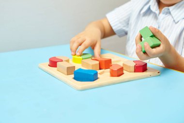 Oğlan odasında oyun oynuyor. Şekil ve renkleri öğreniyorum. Bir çocuk ayırıcıyla oynuyor. Çocuklar için eğitici mantık oyuncakları. Çocuk Gelişimi için Montessori Oyunları.