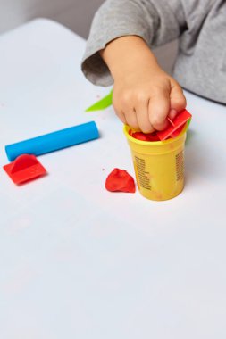 Oğlan odasında oyun oynuyor. Küçük çocuk oyun mu oynuyordu yoksa hamur mu oynuyordu? Çocuklar için eğitici oyuncaklar. Çocuk Gelişimi Oyunları. Çocuğun elleri kil yoğuruyor..