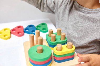 Çocuk bir tasnif makinesi topluyor. Çocuklar için eğitici mantık oyuncakları. Çocukların elleri, yakın plan. Çocuk Gelişimi için Montessori Oyunları. Beyaz arkaplanda çok renkli mantık sıralayıcı.