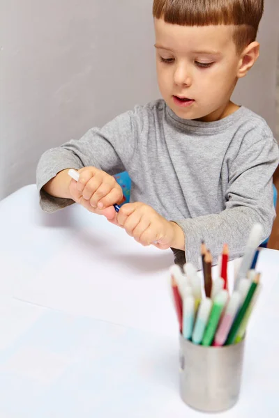 可爱的金发小男孩在家里画彩色铅笔 在白桌上画画 — 图库照片