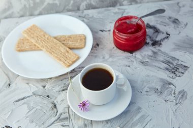 Kahvaltı için reçelli çıtır ekmek ve gri bir arka plan. Köpüklü bir kavanoz taze bal bir fincan kahvenin yanında. En az kalori. uygun beslenme