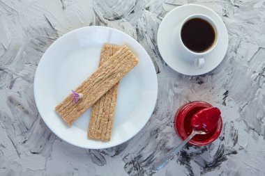 Kahvaltı için reçelli çıtır ekmek ve gri bir arka plan. Köpüklü bir kavanoz taze bal bir fincan kahvenin yanında. En az kalori. uygun beslenme