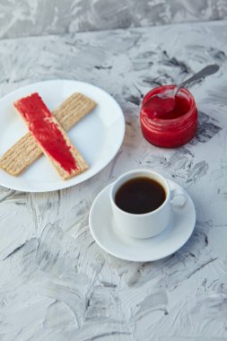 Kahvaltı için reçelli çıtır ekmek ve gri bir arka plan. Köpüklü bir kavanoz taze bal bir fincan kahvenin yanında. En az kalori. uygun beslenme