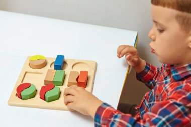 Oğlan odasında oyun oynuyor. Şekil ve renkleri öğreniyorum. Bir çocuk ayırıcıyla oynuyor. Çocuklar için eğitici mantık oyuncakları. Çocuk Gelişimi için Montessori Oyunları.