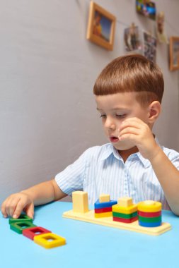 Oğlan odasında oyun oynuyor. Şekil ve renkleri öğreniyorum. Bir çocuk ayırıcıyla oynuyor. Çocuklar için eğitici mantık oyuncakları. Çocuk Gelişimi için Montessori Oyunları.
