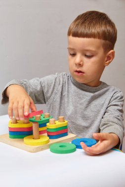 Oğlan odasında oyun oynuyor. Şekil ve renkleri öğreniyorum. Bir çocuk ayırıcıyla oynuyor. Çocuklar için eğitici mantık oyuncakları. Çocuk Gelişimi için Montessori Oyunları.