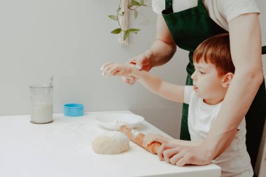 Mutfakta mutlu bir aile. Baba ve oğul hamuru hazırlıyorlar, kurabiye pişiriyorlar. Ev içinde rahat bir yaşam tarzı, güzel bir çocuk, tatil konsepti, merdane, mangalcı ve hamur.. 