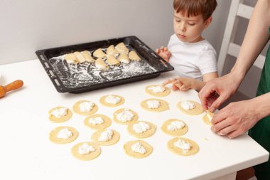 Mutfakta mutlu bir aile. Baba ve oğul hamuru hazırlıyorlar, kurabiye pişiriyorlar. Ev içinde rahat bir yaşam tarzı, güzel bir çocuk, tatil konsepti, merdane, mangalcı ve hamur.. 