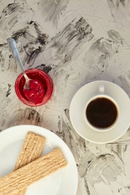 Kahvaltı için reçelli çıtır ekmek ve gri bir arka plan. Köpüklü bir kavanoz taze bal bir fincan kahvenin yanında. En az kalori. uygun beslenme