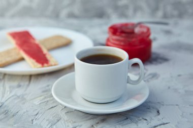 Kahvaltı için reçelli çıtır ekmek ve gri bir arka plan. Köpüklü bir kavanoz taze bal bir fincan kahvenin yanında. En az kalori. uygun beslenme