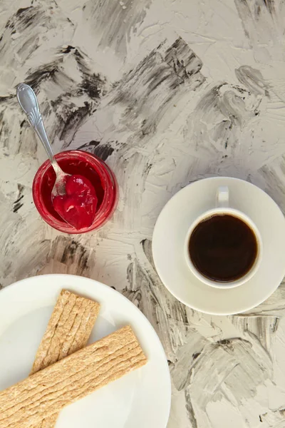 Kahvaltı için reçelli çıtır ekmek ve gri bir arka plan. Köpüklü bir kavanoz taze bal bir fincan kahvenin yanında. En az kalori. uygun beslenme