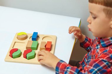Oğlan odasında oyun oynuyor. Şekil ve renkleri öğreniyorum. Bir çocuk ayırıcıyla oynuyor. Çocuklar için eğitici mantık oyuncakları. Çocuk Gelişimi için Montessori Oyunları.