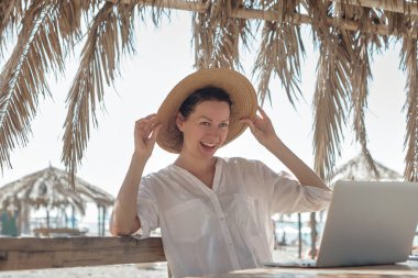 Kumsalda dizüstü bilgisayar kullanan genç bir kadın. Serbest çalışma kavramı