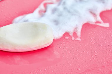 Yıkama konsepti. Köpük köpükler ve pembe arka planda bir kalıp sabun. Temizlik servisi