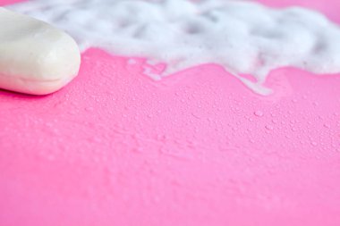 Yıkama konsepti. Köpük köpükler ve pembe arka planda bir kalıp sabun. Temizlik servisi