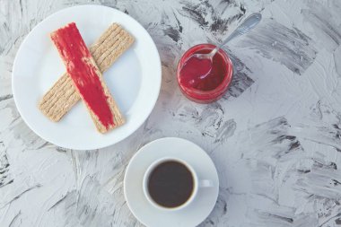 Kahvaltı için reçelli çıtır ekmek ve gri bir arka plan. Köpüklü bir kavanoz taze bal bir fincan kahvenin yanında. En az kalori. uygun beslenme