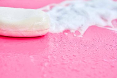 Yıkama konsepti. Köpük köpükler ve pembe arka planda bir kalıp sabun. Temizlik servisi