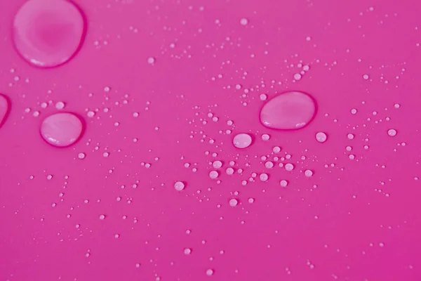 Full frame of the textures formed by the bubbles and drops of water. Drops of water spilled on a light pink surface